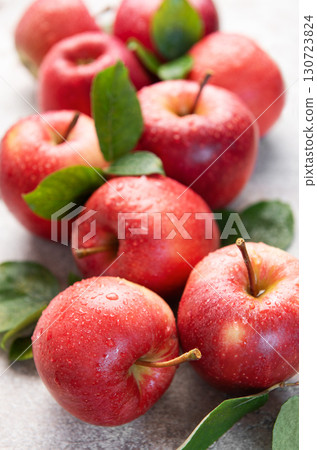 Fresh red apples with water drops and green leaves on gray background Fresh red apples with water drops and green leaves on gray background 130723824