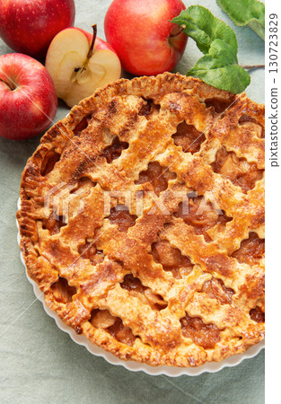 Freshly baked apple pie with red apples and leaves on green tablecloth 130723829