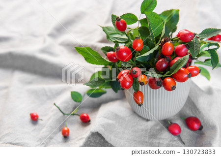 Rose hips spilling from a vase create a vibrant display of autumnal colors 130723833