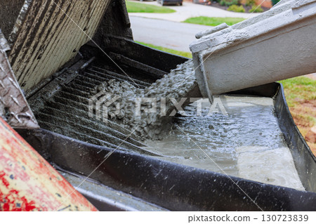 Worker pours fresh concrete into mixer at home construction site during works constructed day Worker pours fresh concrete into mixer at home construction site during works constructed day 130723839