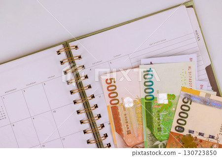 South Korean won banknotes are placed on an open planner, indicating financial planning budgeting 130723850