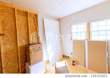 Sunlight floods room under renovation, showcasing drywall sheets tools ready for installation during works daytime renovations 130723851