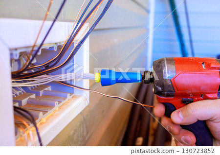 Electrician operates drill to connect wiring in residential exterior wall in broad works day Electrician operates drill to connect wiring in residential exterior wall in broad works day 130723852