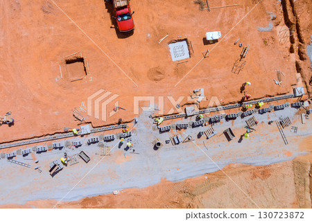 Workers collaborate on laying down concrete blocks for building foundation under works day Workers collaborate on laying down concrete blocks for building foundation under works day 130723872
