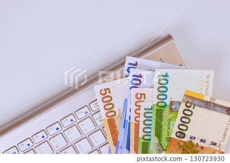 Various South Korean won currency notes placed alongside laptop keyboard highlight connection between money technology. Various South Korean won currency notes placed alongside laptop keyboard highlight connection between money technology. 130723930
