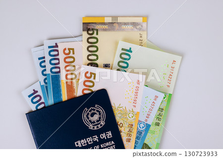Stack of South Korean won banknotes arranged with dark Korean passport, showcasing currency identity together. 130723933
