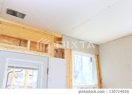 Unfinished interior renovation shows drywall installation exposed framing in residential setting. 130724038