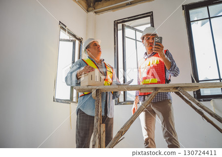 Engineers analyzing house model together during indoor construction planning with precision and leadership 130724411