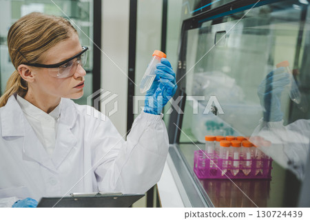Biological researcher holding test tube inside laboratory with sterilized environment and modern tools Biological researcher holding test tube inside laboratory with sterilized environment and modern tools 130724439
