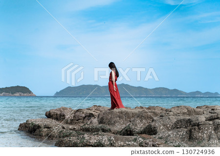 一位身穿紅裙的女子站在海灘上④ 130724936