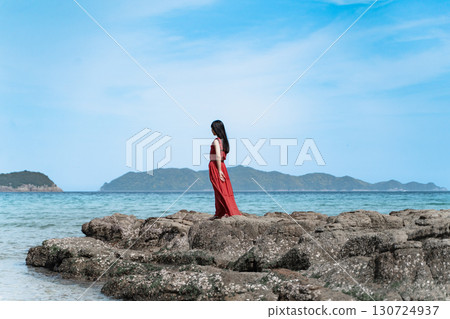 A woman in a red dress standing on the beach ⑤ A woman in a red dress standing on the beach ⑤ 130724937