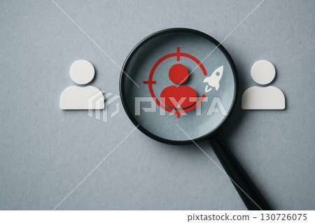 Recruitment process concept with employee selection symbolized by magnifying glass focusing on red figure among white figures, representing talent search and hiring strategy 130726075
