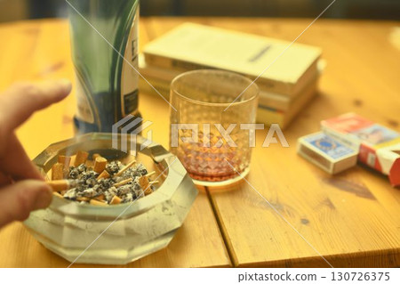 A hand holding a smoking tobacco cigarette. A hand holding a smoking tobacco cigarette. The concept of alcoholism, tobaccoism, and dependence. A hand holding a smoking tobacco cigarette. A hand holding a smoking tobacco cigarette. The concept of alcoholism, tobaccoism, and dependence. 130726375