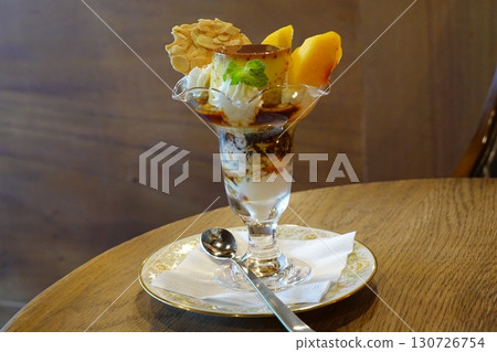 Creamy pudding a la mode topped with fresh fruits and a scoop of ice cream, offering a perfect harmony of smooth, sweet, and refreshing flavors in every elegant and delightful spoonful. 130726754