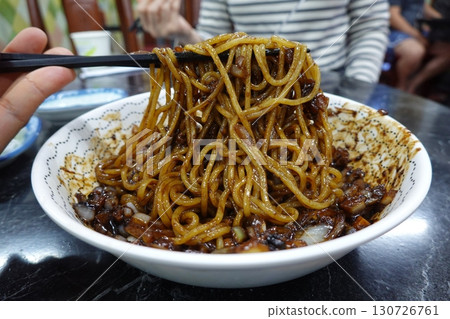 Classic jajangmyeon with thick noodles in a rich black bean sauce, garnished with sliced cucumber and sesame seeds. A beloved Korean-Chinese comfort dish, full of savory depth and flavor. 130726761