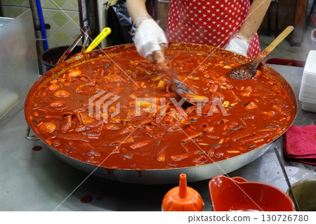 Spicy Korean tteokbokki with chewy rice cakes in a vibrant red sauce, topped with sesame seeds and green onions. A popular street food known for its addictive flavor and satisfying texture. 130726780