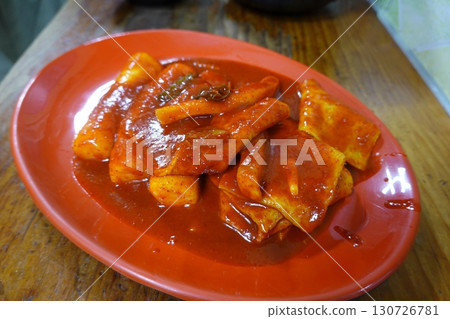 Spicy Korean tteokbokki with chewy rice cakes in a vibrant red sauce, topped with sesame seeds and green onions. A popular street food known for its addictive flavor and satisfying texture. Spicy Korean tteokbokki with chewy rice cakes in a vibrant red sauce, topped with sesame seeds and green onions. A popular street food known for its addictive flavor and satisfying texture. 130726781