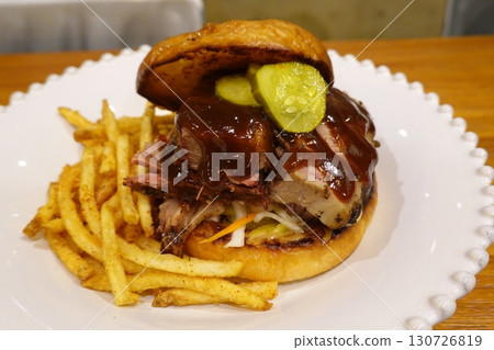 A classic combination of a juicy burger with fresh toppings served alongside golden, crispy French fries. Perfect for a satisfying meal that blends savory flavors and crunchy textures. 130726819