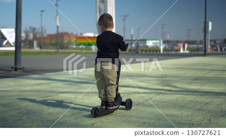 A Happy Child Riding a Bright Scooter in the Open Park, Enjoying an Adventurous Day A Happy Child Riding a Bright Scooter in the Open Park, Enjoying an Adventurous Day 130727621