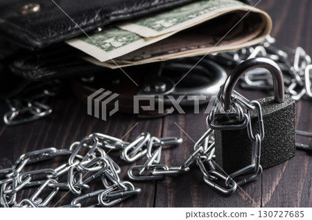 A wallet filled with money is chained in a heavy metal chain A wallet filled with money is chained in a heavy metal chain 130727685