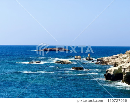 Picturesque beach, waves crashing on the sandy shore. Sea waves beat against the rocks. Cyprus Island, umbrellas, tourist boats, Mediterranean Sea. Picturesque beach, waves crashing on the sandy shore. Sea waves beat against the rocks. Cyprus Island, umbrellas, tourist boats, Mediterranean Sea. 130727936