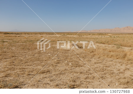 Arid desert landscape in balkh province afghanistan with distant mountains and a clear sky Arid desert landscape in balkh province afghanistan with distant mountains and a clear sky 130727988