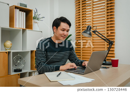 happy man working with laptop computer at home office 130728446
