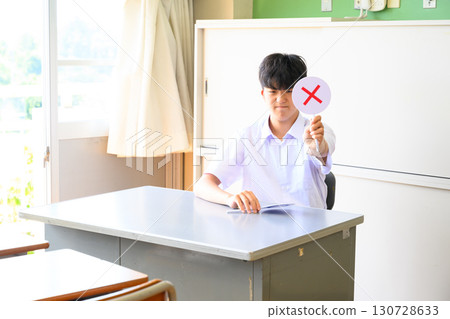 Male student answering a quiz in a school classroom. A learning scene where students answer with true or false questions. 130728633