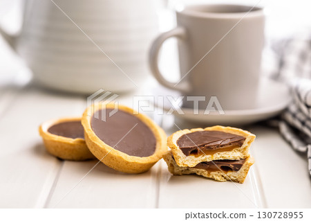 Sweet chocolate tartelettes and coffee cup on white table. 130728955