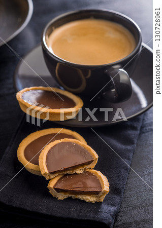 Sweet chocolate tartelettes on black table. Sweet chocolate tartelettes on black table. 130728961