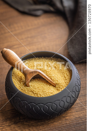 Uncooked couscous in bowl on wooden table. Uncooked couscous in bowl on wooden table. 130728970