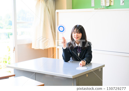 女學生正在回答測驗。這是一張在學校教室裡標記「是」或「否」的教育圖片。 女學生正在回答測驗。這是一張在學校教室裡標記「是」或「否」的教育圖片。 130729277