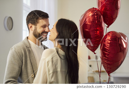 Happy couple standing close, hugging and kissing, celebrating Valentine Day in romantic atmosphere. Happy couple standing close, hugging and kissing, celebrating Valentine Day in romantic atmosphere. 130729290