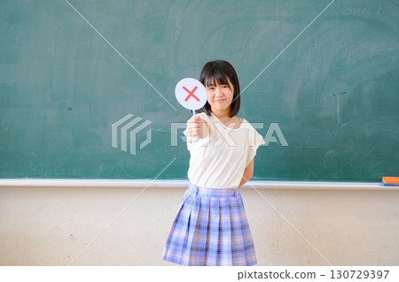 女學生正在回答測驗。這是一張在學校教室裡標記「是」或「否」的教育圖片。 女學生正在回答測驗。這是一張在學校教室裡標記「是」或「否」的教育圖片。 130729397