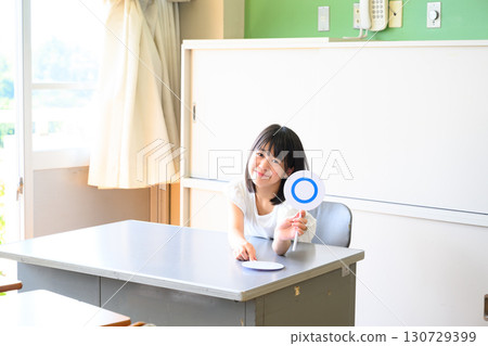 Female students answering a quiz. Educational image of marking yes or no in a school classroom. Female students answering a quiz. Educational image of marking yes or no in a school classroom. 130729399