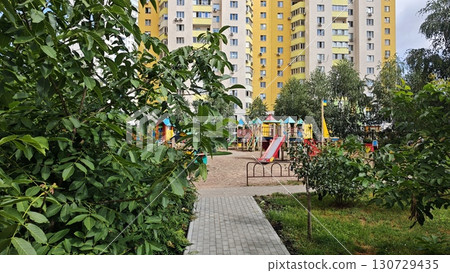 Colorful playground surrounded by greenery with high-rise apartment buildings in the background 130729435