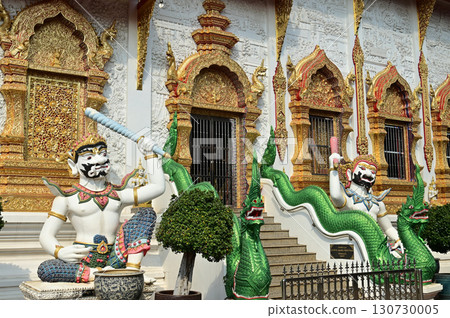 Statues of sitting white Giant holding a baton in Thai art, decorate the front of the Church or Chapel at Wat Den Sali Si Mueang Kaen temple. Located at Chaing Mai Province in Thailand. 130730005