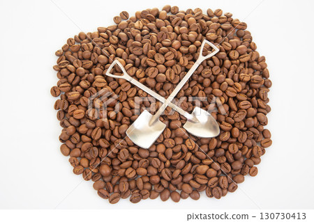Detailed shot of crossed shovels resting on a sea of roasted coffee beans Detailed shot of crossed shovels resting on a sea of roasted coffee beans 130730413