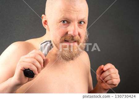 Bearded man with trimmer to adjust beard in hand. grooming and fashionable style barbershop 130730424