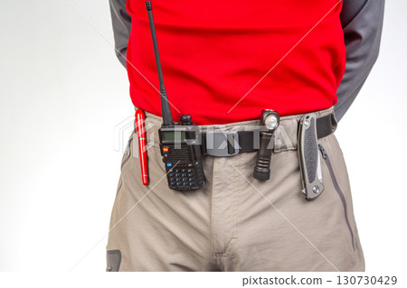 Pen, walkie-talkie, knife and flashlight with clips on the waistband of trekking pants. EDC items Pen, walkie-talkie, knife and flashlight with clips on the waistband of trekking pants. EDC items 130730429