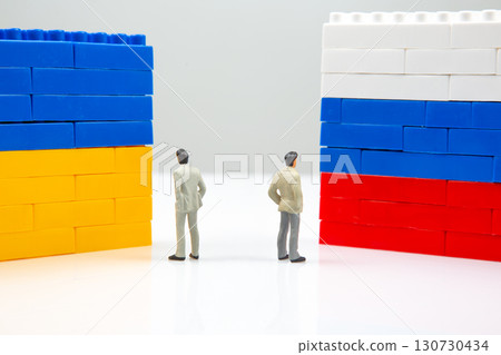 depiction of division with miniature people flanked by blocks walls in Ukrainian and Russian flag  130730434