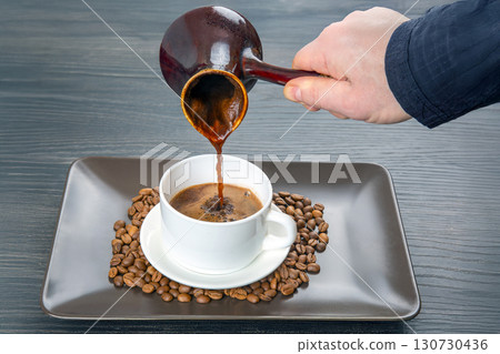 Traditional Turkish coffee is poured from a cezve into a pristine white cup Traditional Turkish coffee is poured from a cezve into a pristine white cup 130730436