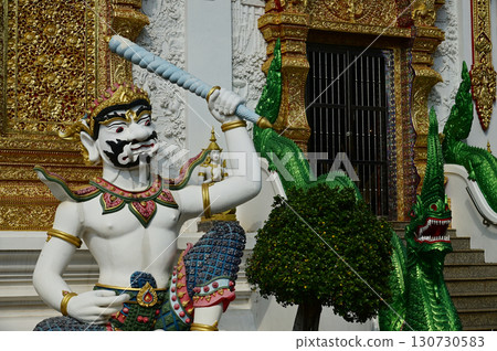 Statues of sitting white Giant holding a baton in Thai art, decorate the front of the Church or Chapel at Wat Den Sali Si Mueang Kaen temple. Located at Chaing Mai Province in Thailand. Statues of sitting white Giant holding a baton in Thai art, decorate the front of the Church or Chapel at Wat Den Sali Si Mueang Kaen temple. Located at Chaing Mai Province in Thailand. 130730583
