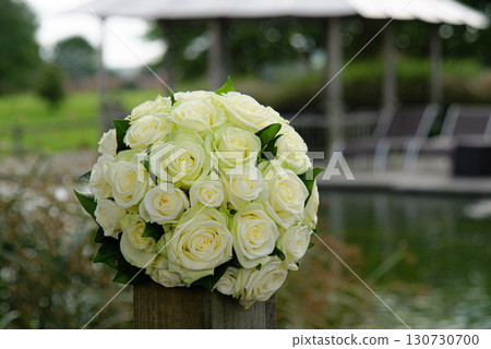 Elegant White Rose Bouquet on Wooden Post by a Tranquil Pond Elegant White Rose Bouquet on Wooden Post by a Tranquil Pond 130730700