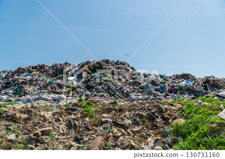 Huge outdoor landfill site with mountains of diverse garbage, plastic waste, and refuse under a clear blue sky. Environmental pollution. Huge outdoor landfill site with mountains of diverse garbage, plastic waste, and refuse under a clear blue sky. Environmental pollution. 130731160