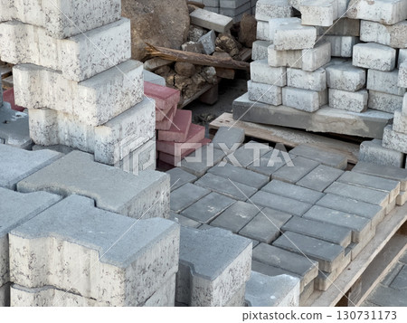 Stacked grey and red concrete paving blocks and bricks on wooden pallets. Construction materials for building roads and paths outdoors. Stacked grey and red concrete paving blocks and bricks on wooden pallets. Construction materials for building roads and paths outdoors. 130731173