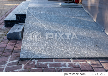 Textured grey granite slabs connect with red brick pavement. Stone steps lead to an urban outdoor path. Durable modern material surface detail. Textured grey granite slabs connect with red brick pavement. Stone steps lead to an urban outdoor path. Durable modern material surface detail. 130731212