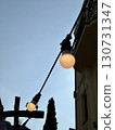 Retro string lights with glowing bulbs hanging outdoors against blue sky, balcony railing, and building silhouette, warm evening lighting for urban lifestyle and design concept 130731347