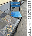 Vivid blue painted chair and ornate tiled table on stone pavement, vibrant urban seating, artistic design, travel, relaxation, and street lifestyle concept 130731358