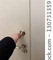 Hand turning round metal lock on white door, closeup home security, safe entry, protection, apartment lifestyle, access control, and safety concept 130731359